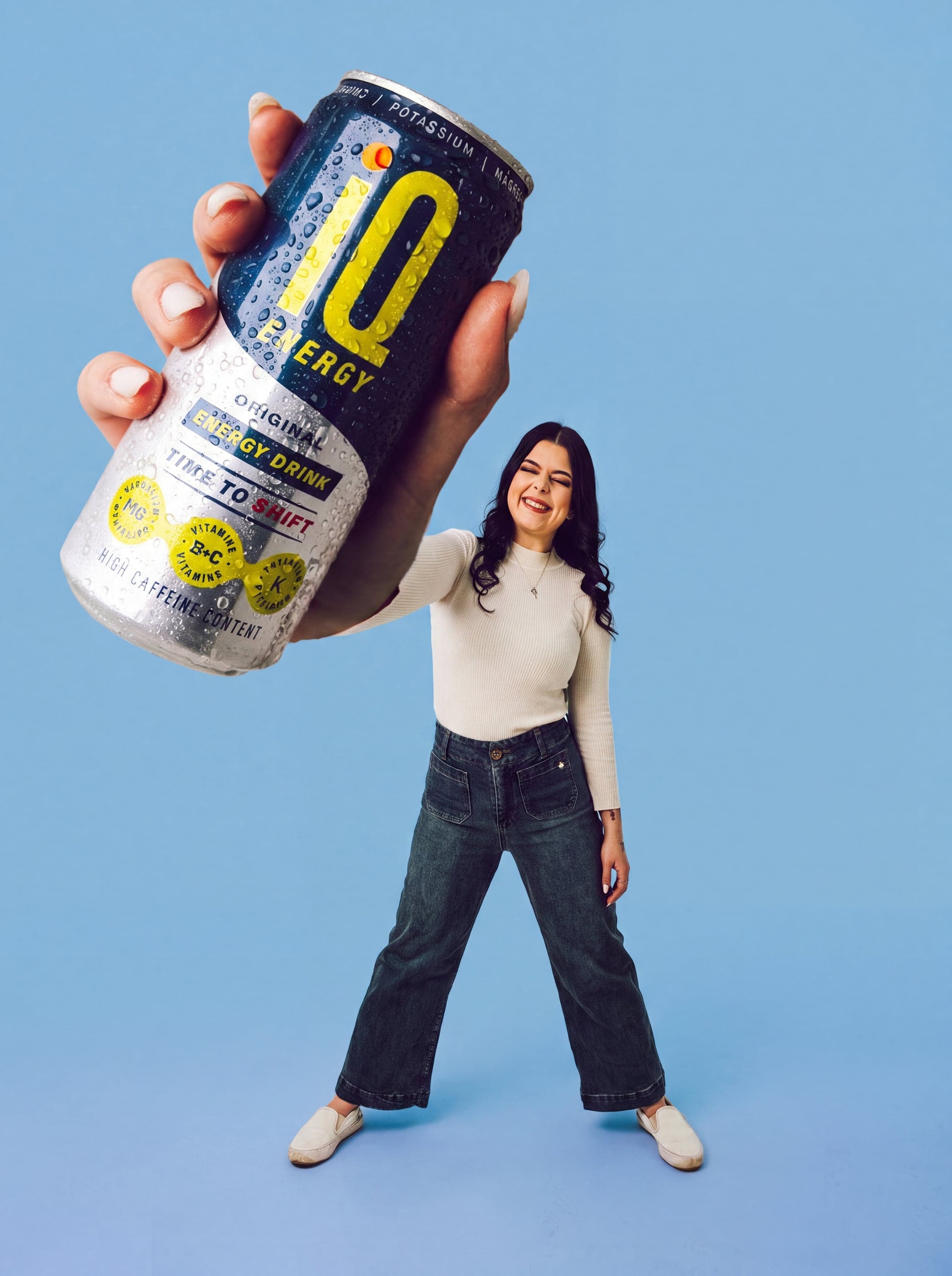 Oversized can held over a model on pale blue
