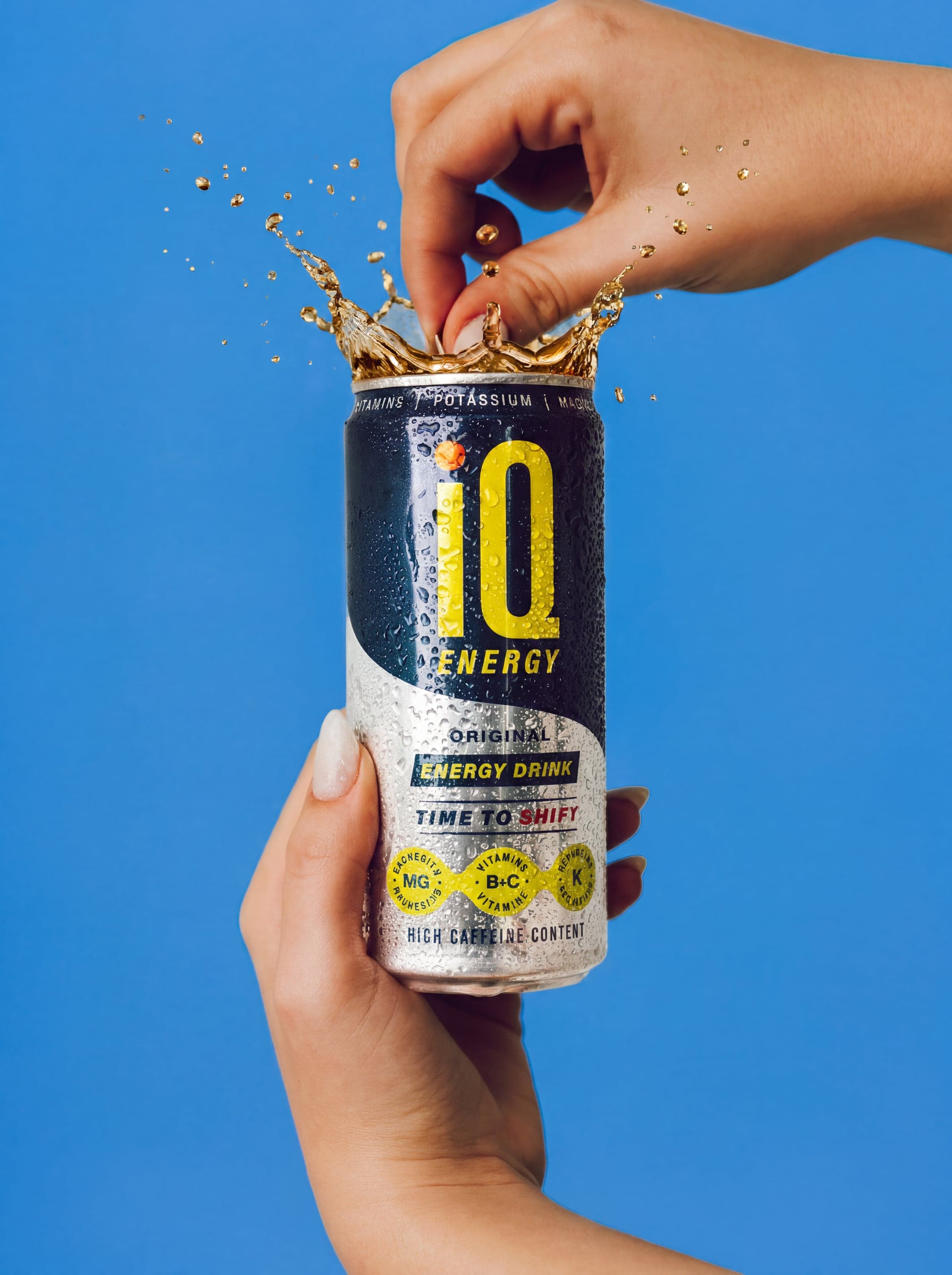 Hand cracking open a can, liquid splashing
