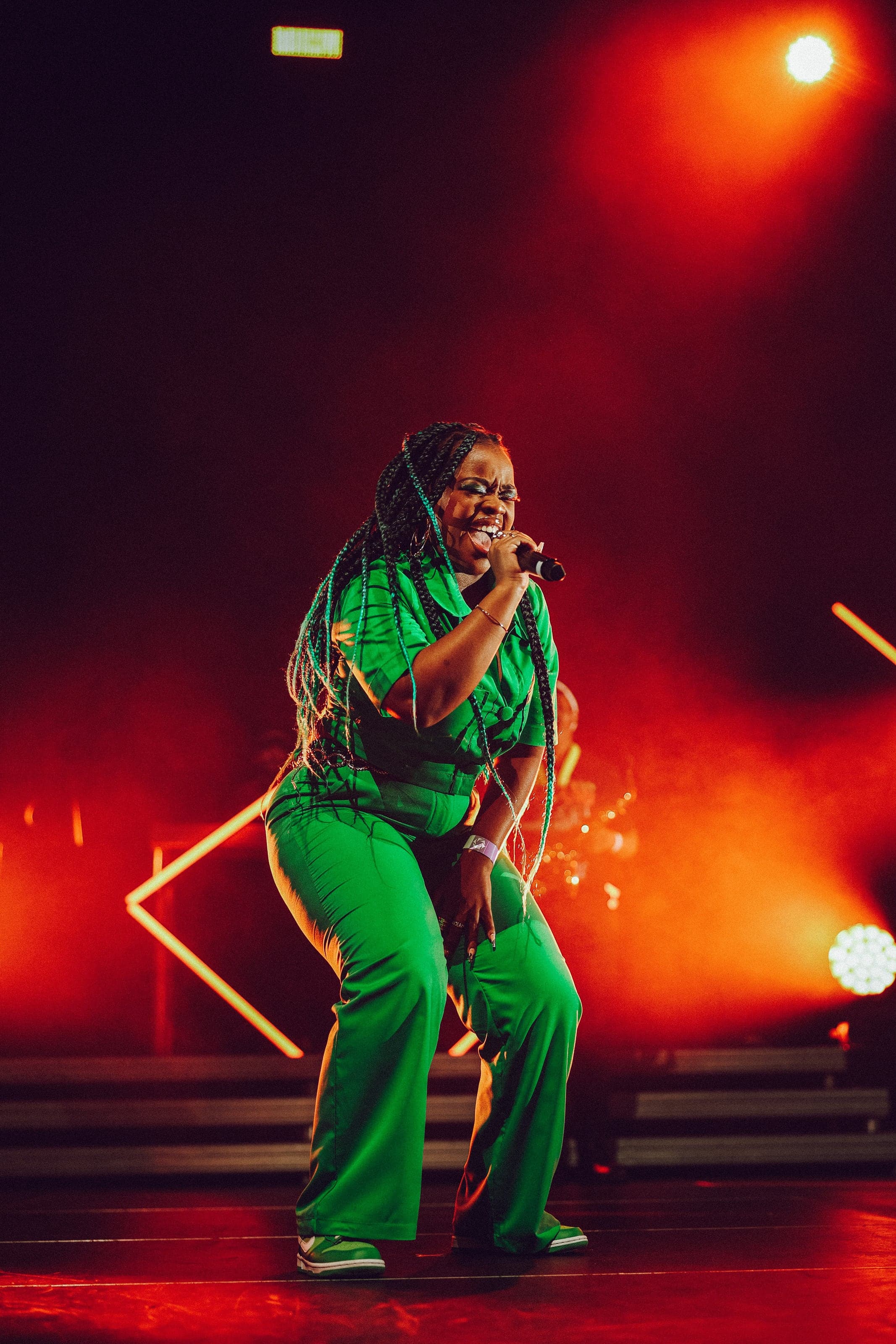 Singer in green on a red-lit stage