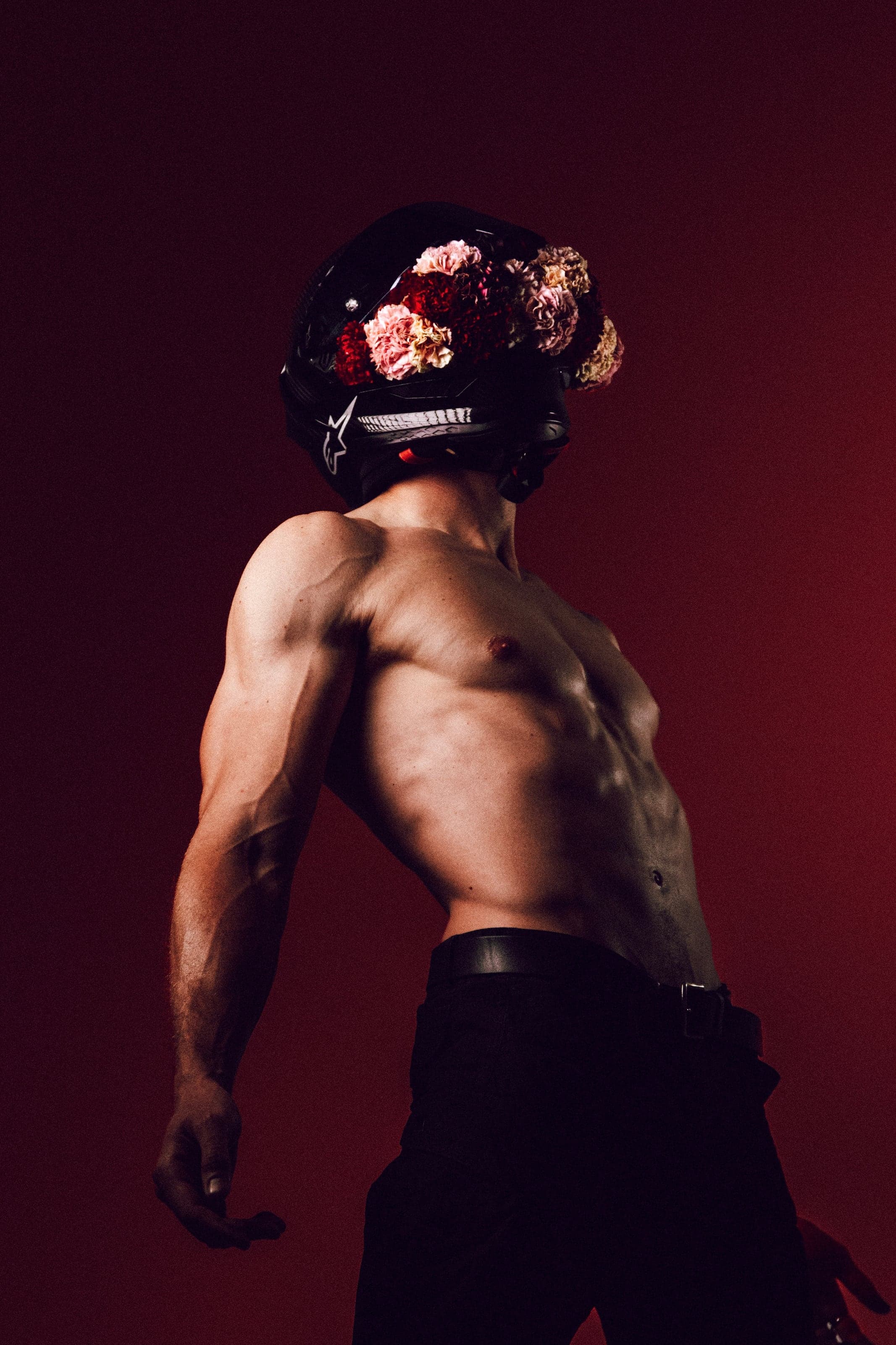 Shirtless man in a flower-covered helmet on oxblood