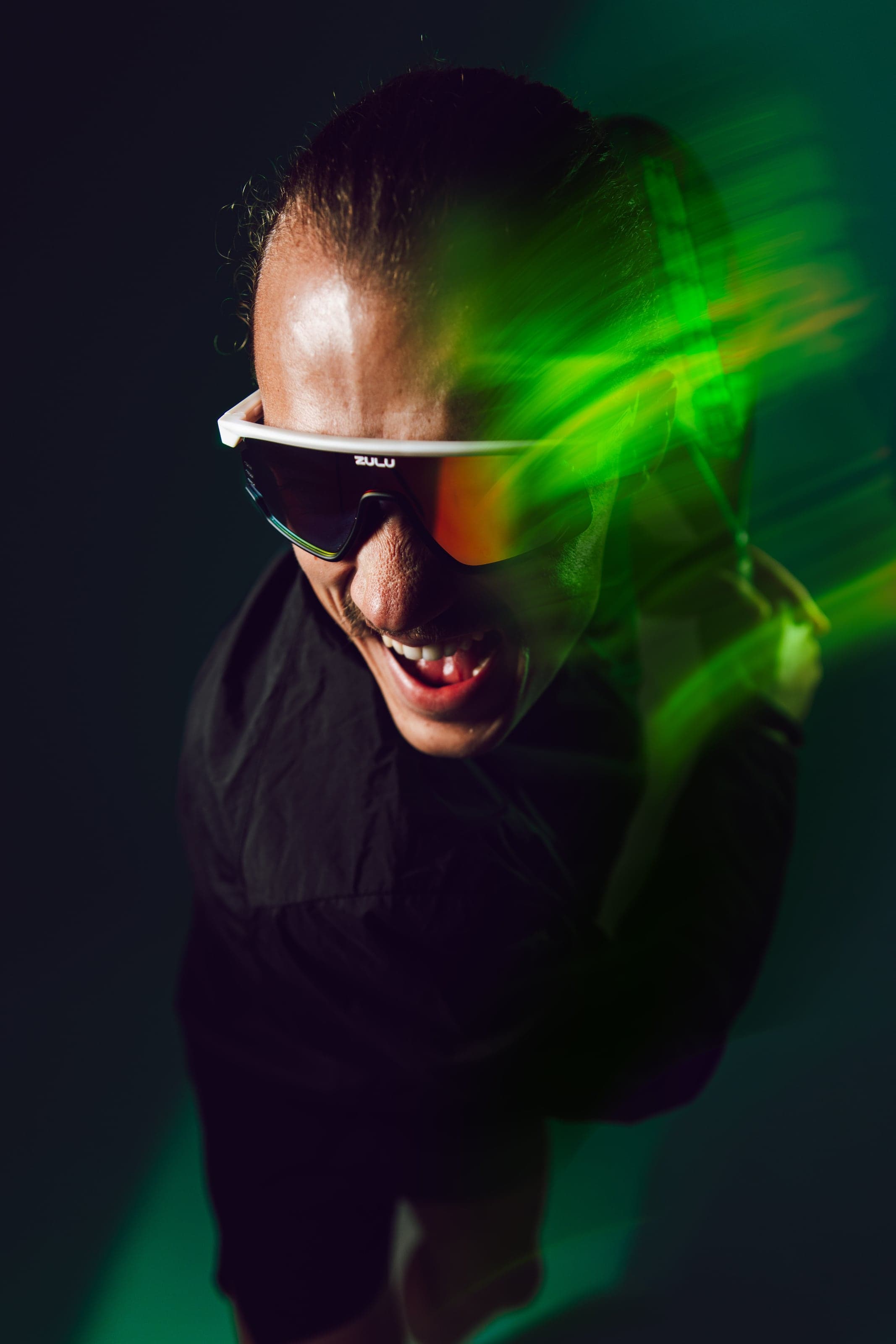 Laughing man in white glasses with a green light trail across his face