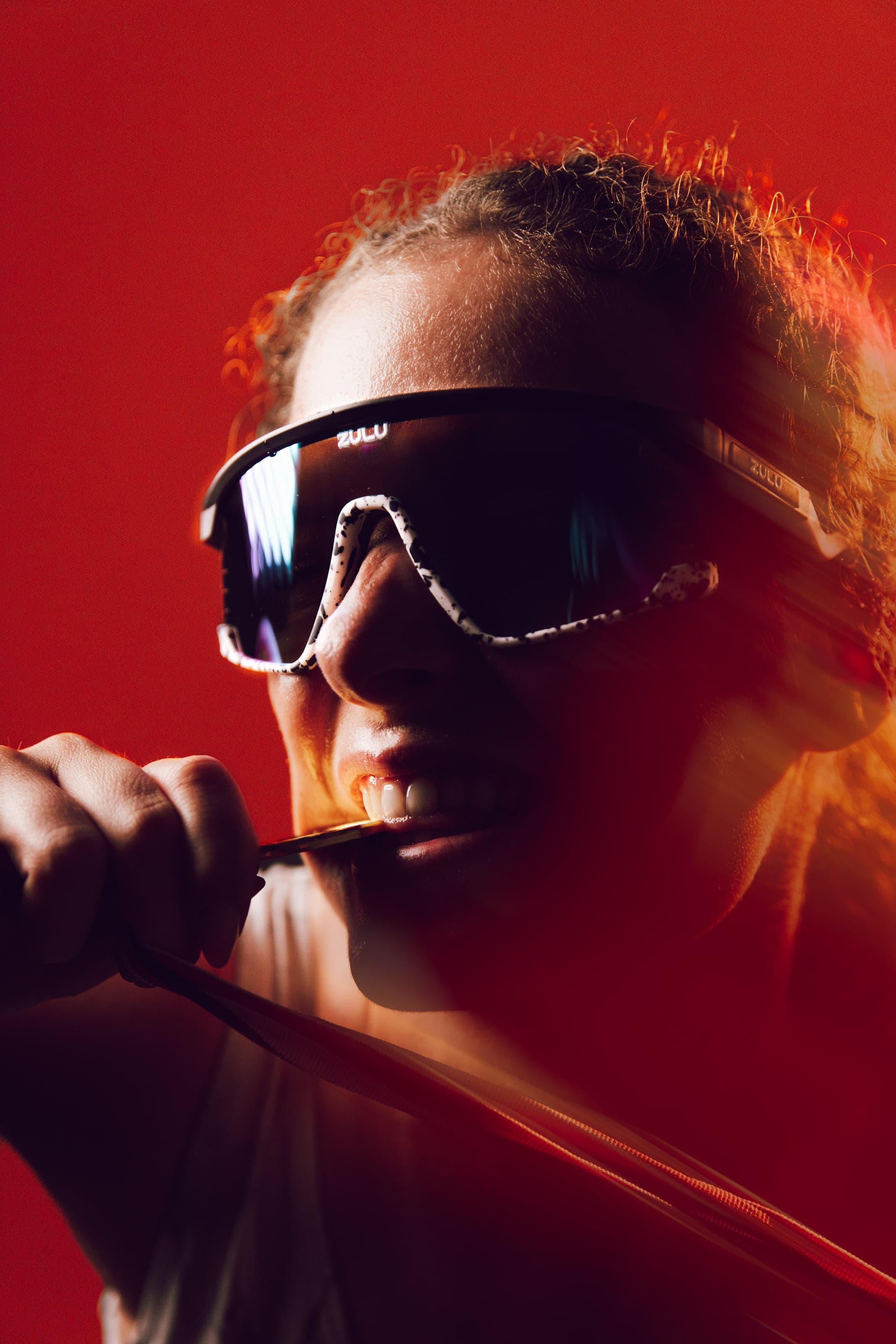 Woman biting a red rod under orange light, motion blurred
