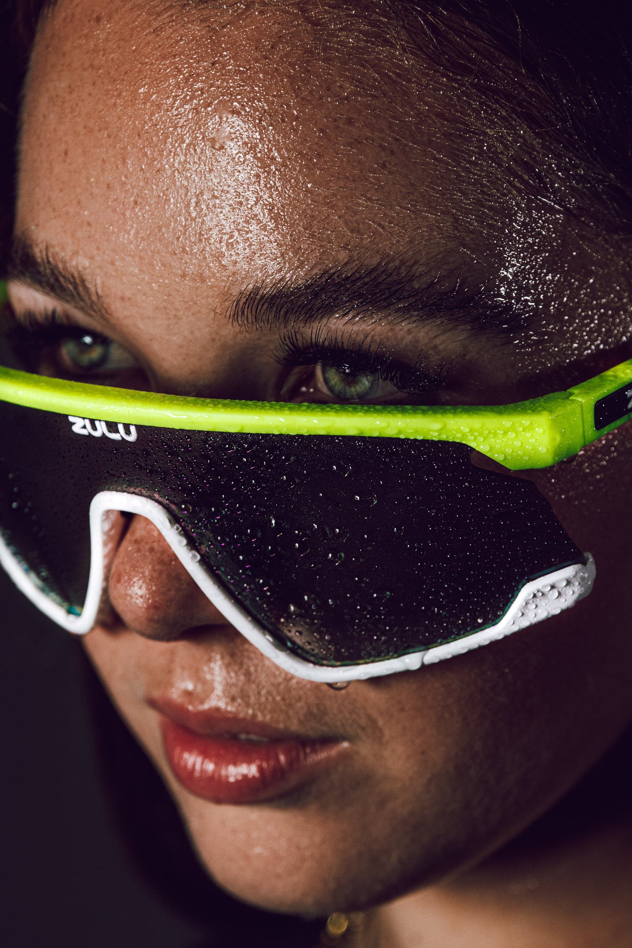 Close portrait in neon green sports glasses, skin beaded with water