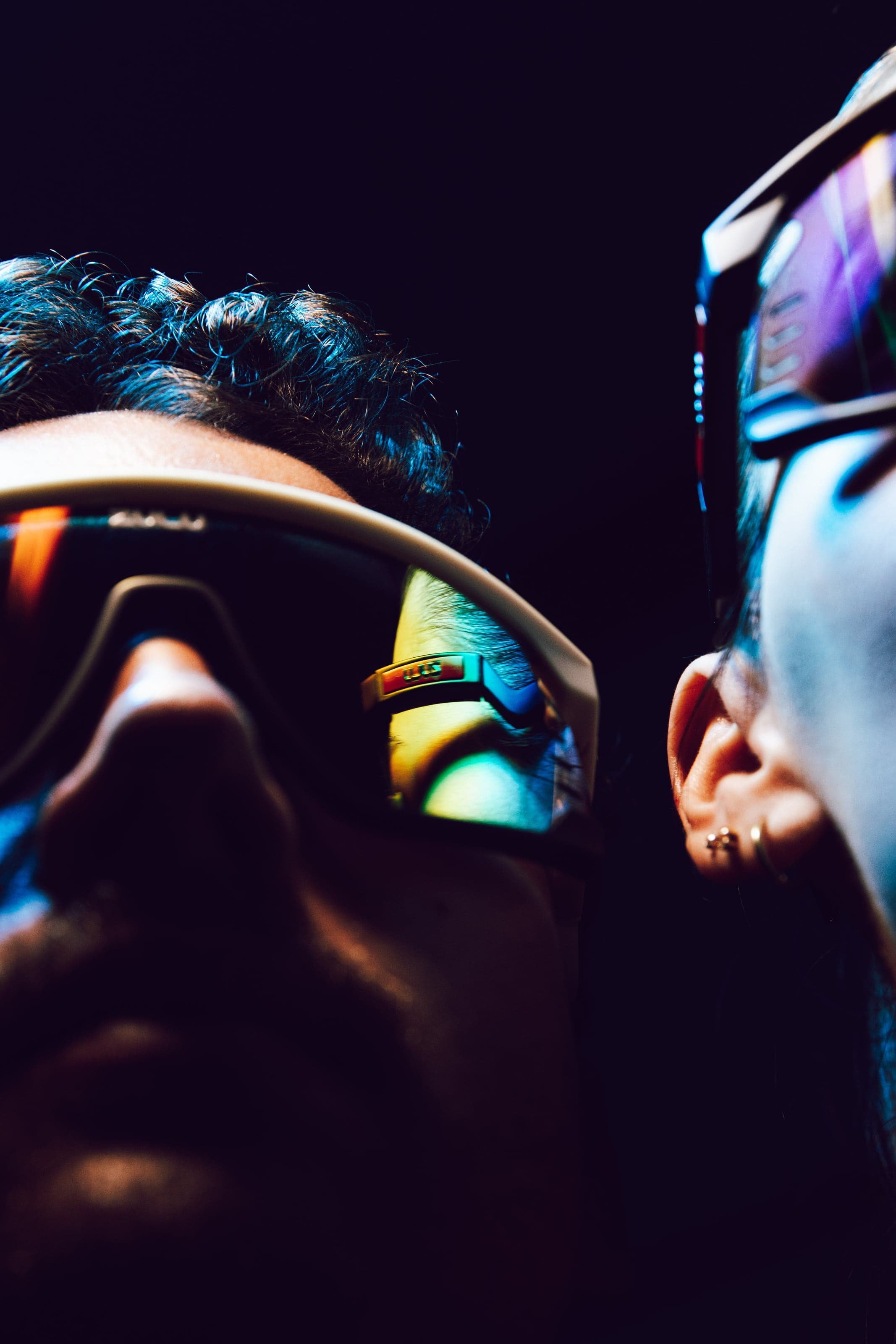 Two faces in mirrored glasses under hard blue light